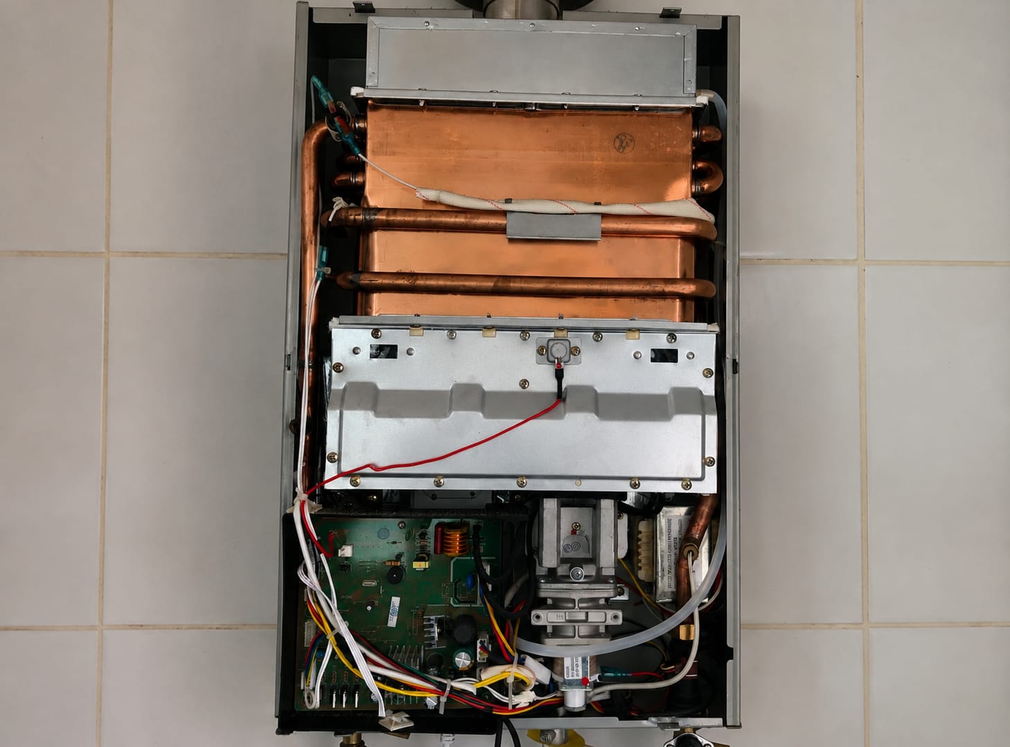 Aquecedor a gás aberto durante manutenção, com trocador de calor e placa eletrônica à vista